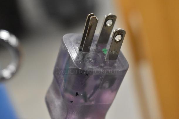 Close-up of a three-pin electrical plug with a transparent casing, showing a metallic prong with marking "085."