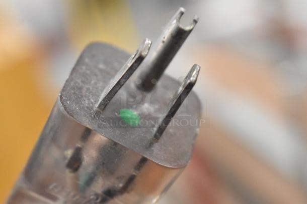 Close-up of a plug with three prongs, featuring a green dot marking. Visible wear suggests used condition.