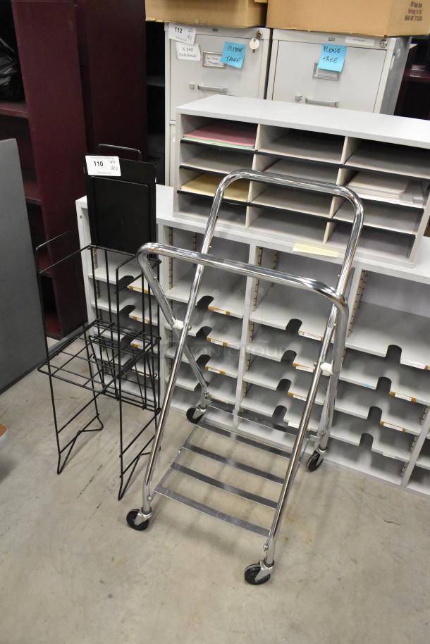 Laundry bag frame on casters and a metal newspaper stand. Both items in good condition, black and chrome finishes. Lot includes 2 of each.