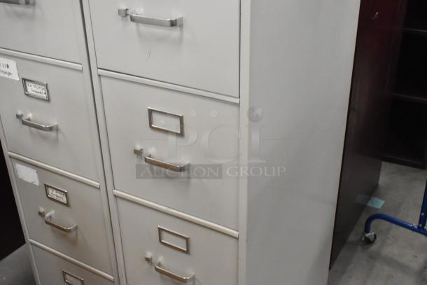 2 gray metal 4-drawer filing cabinets, each with label holders and silver handles, showing signs of use.