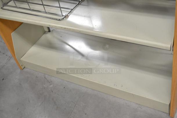 Metal and wood book shelf with two shelves, showing some wear. Includes metal wire basket on top.