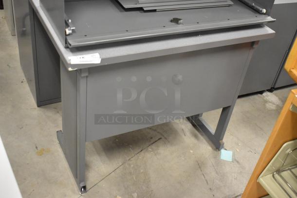 Gray desk with overhead cabinet, metal construction, good condition, visible label with item details.