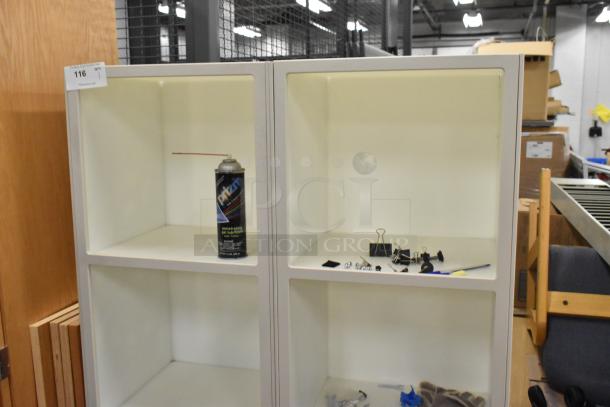 8 cubby shelving unit with white finish, used. Contains a can of lubricant and assorted office supplies in cubbies.