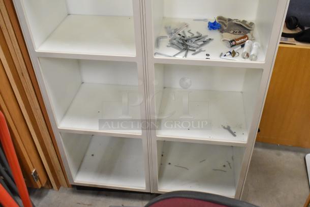 White 8 cubby shelving unit, signs of wear, various tools, and items inside, suitable for storage or organization.
