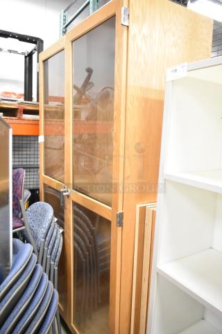 Wooden 2 Door Merchandising Cabinet with glass panels, metal handles, and hinges. Good condition, tall and spacious design.