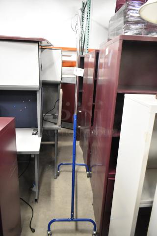 Metal coat rack on casters, featuring a chrome finish and blue frame. Item has a tag indicating quantity.