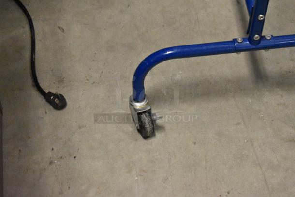 Blue metal coat rack on casters, showing detail of one wheel. Appears sturdy, in good condition.