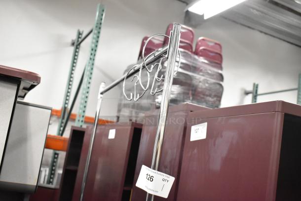 Metal coat rack on casters, chrome finish, sturdy frame. Auction tag labeled "126" visible. Ideal for easy mobility.