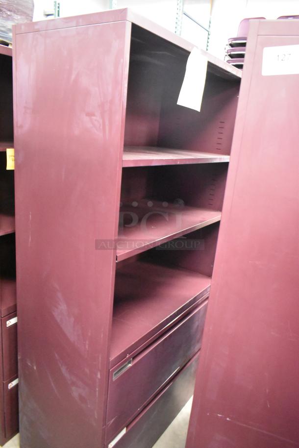 Two maroon metal bookshelves, each with three adjustable shelves and storage below, showing minor wear, ideal for office use.