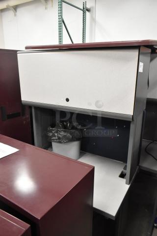 Light gray desk with overhead cabinet; includes maroon accents and features storage space. Suitable for office use.