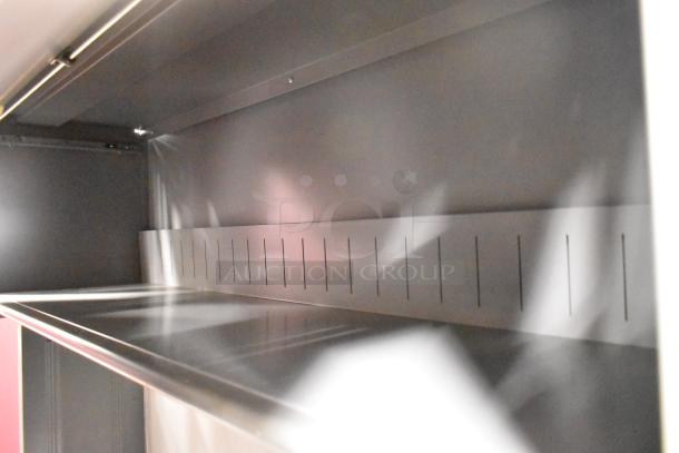 Light gray overhead cabinet interior, part of a 2 desk set. Clean condition, metal surface, slotted panel design.