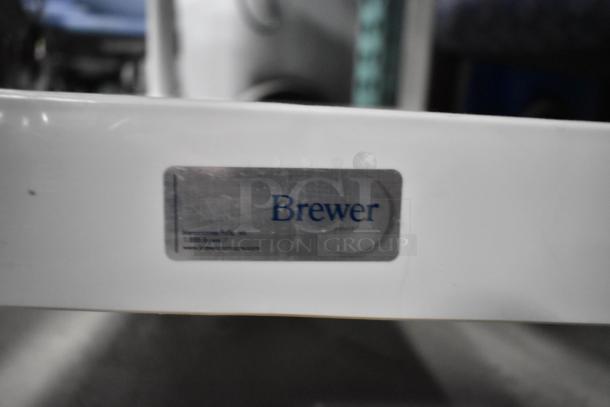 Brewer 3 tier cart on casters; white with visible label. Adjustable, sturdy, ideal for storage and transport.