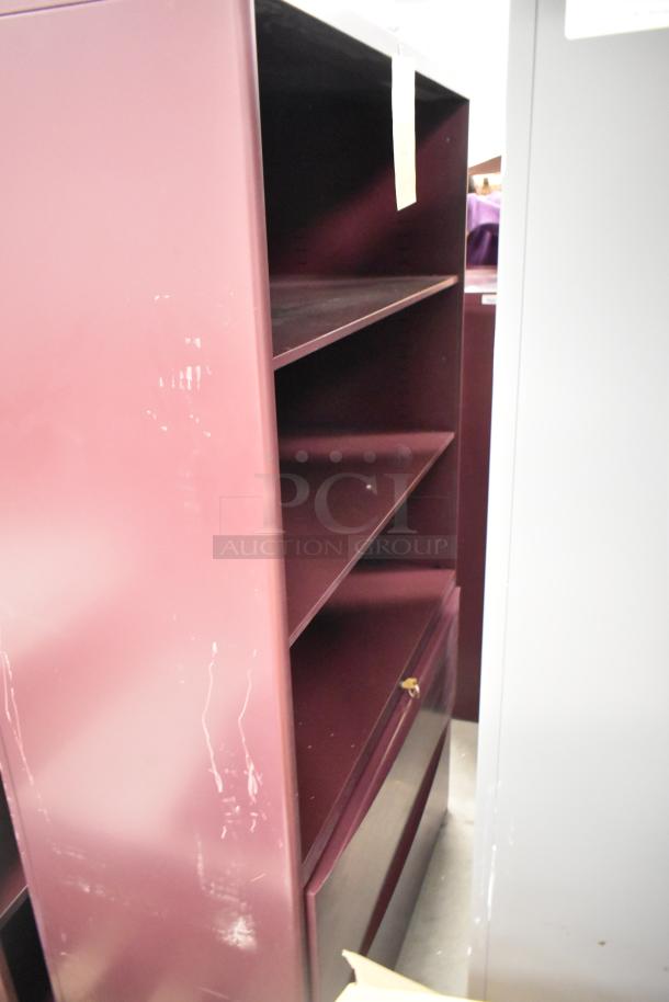 Two metal bookshelves; one maroon, one gray. Features multiple shelves, visible wear on maroon surface. Auction lot includes both.