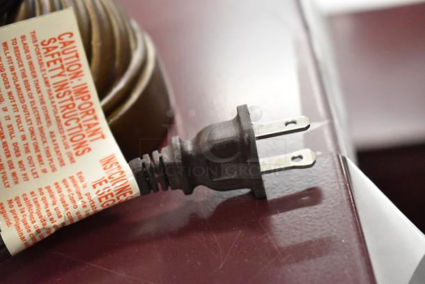 Power cord with safety instruction tag for various lamps, highlighting caution details in English and Spanish.