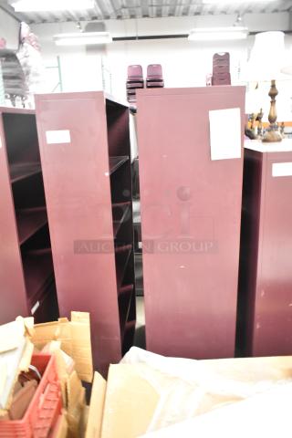 Two maroon metal book shelves, varying styles. Includes visible labels. Good condition. Auction offers 2x your bid.