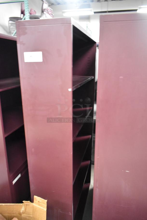 Two maroon metal bookshelves with multiple shelves, used condition, label visible.