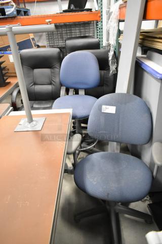 Six assorted office chairs, including black leather and blue fabric types, in used condition. Label marked "147" visible.