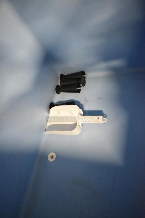 Alt Text: Interior of commercial ice bin with plastic scoop and black components. Clean, well-maintained condition.