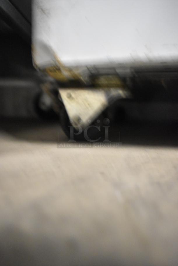 Blurry close-up of the caster on an SD-151 metal commercial chest freezer merchandiser, 115 volts, 1 phase.