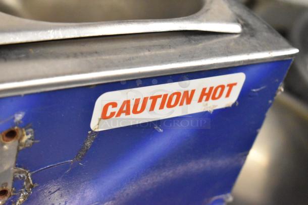 Metal countertop food warmer with "Caution Hot" label, 120 volts, 1 phase, shows signs of wear, blue exterior.