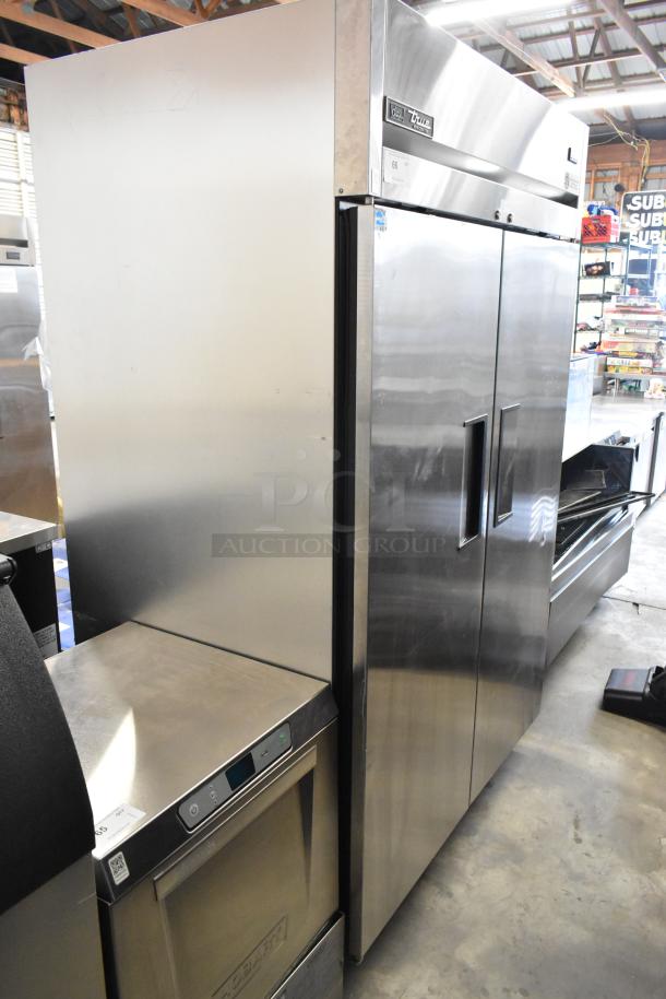 2018 True TG2R-2S-HC stainless steel commercial 2-door reach-in cooler with poly coated racks. Equipped with commercial casters.