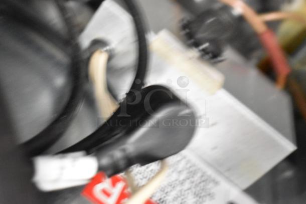 Blurred image of Delfield undercounter cooler's technical area, showing cables and components. Details unclear.