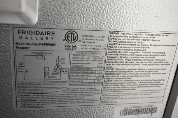 Frigidaire Gallery FGFRF699 upright freezer detail. ETL certification, model info, warnings visible on metal surface.