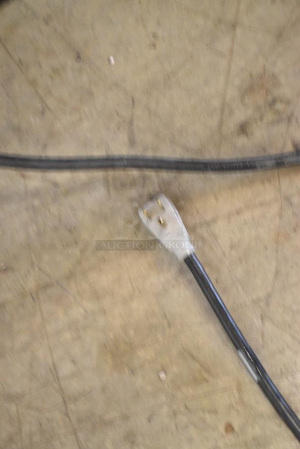 Power cord with three-prong plug on a concrete floor. Suitable for the True GDM-41SL-48-HC-LD cooler.