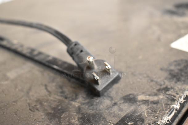 Frigidaire EFMIS155 mini cooler power cord, showing three-prong plug, on dusty surface. 115 volts, 1 phase.