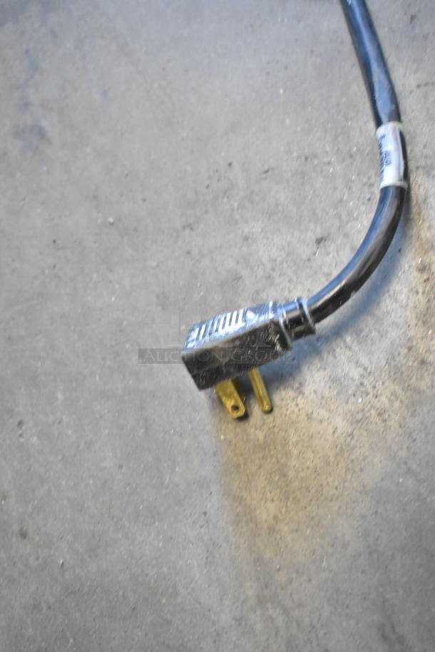 Close-up of a power cord plug on a concrete floor, likely from the 2018 True T-35 commercial cooler.