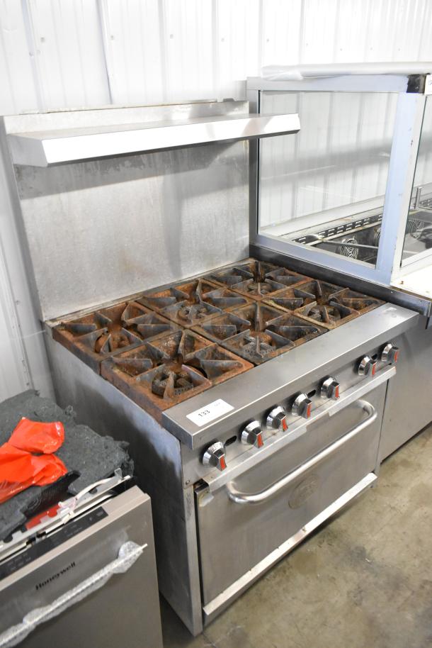Cooking Performance Group stainless steel 6-burner gas range with oven, backsplash, and overshelf. Shows signs of wear.