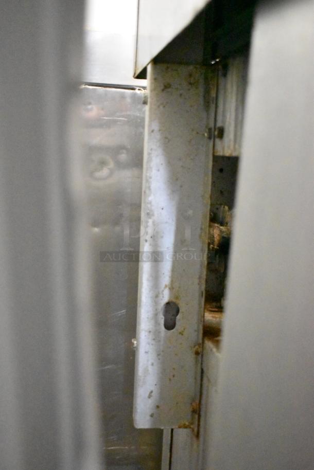 Cooking Performance Group stainless steel 6-burner gas range with oven, backsplash, and overshelf; showing signs of wear.