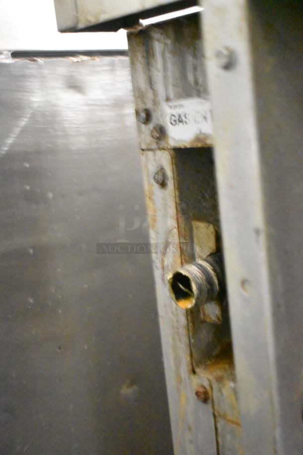 Cooking Performance Group gas-powered 6-burner range connector, visible rust, "Gas" label, commercial-grade stainless steel.