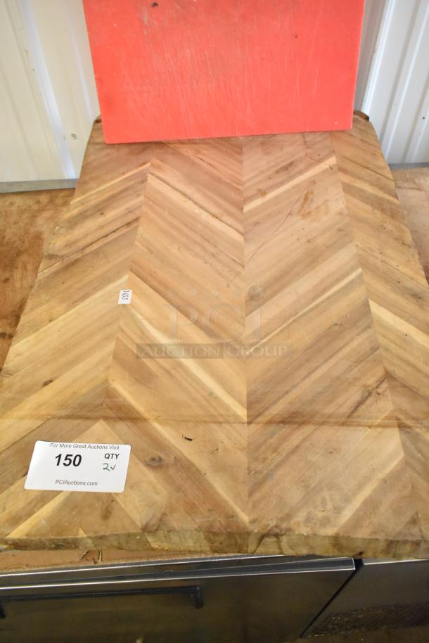 Red and wooden cutting boards, both showing wear. Wooden board with chevron pattern; auction tag reads "150, QTY 2".