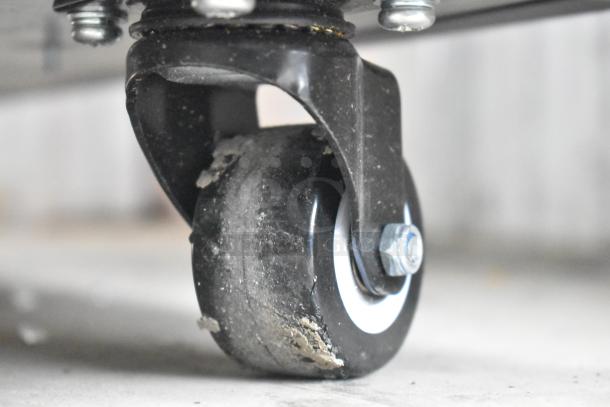 Close-up of a caster wheel from the Avantco Black Extra Deep Vertical Open Air Merchandiser, showing mild wear and usage.