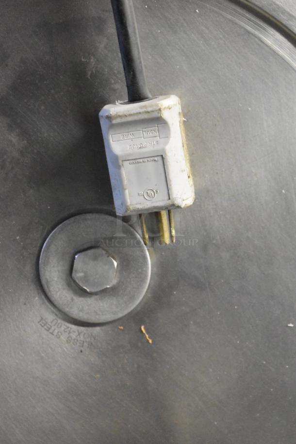 Metal countertop meat slicer, missing carriage. Features 115 volts, 1 phase. Close-up shows electrical plug and stainless steel components.