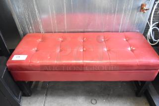 Red bench with tufted leather upholstery, black legs, and ticket number 175. Appears in good condition.