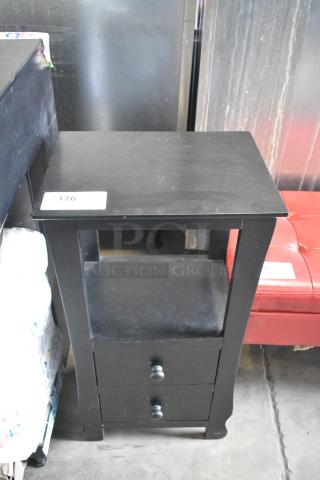 Black wood pattern end table with two drawers, rectangular top, and visible wear. Tag with number 176 displayed.