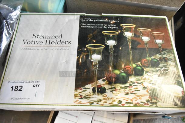 Set of five stemmed votive holders with gold trim, ideal for holiday decor. Box shows decorative setup and product description.