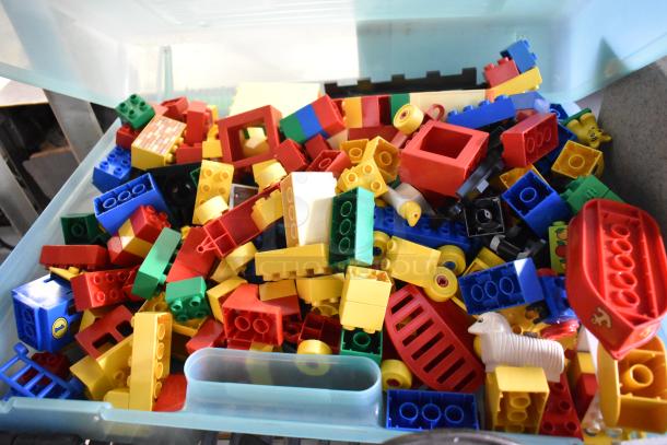 Lot of Lego building blocks in bright colors stored in a hard plastic case. Various shapes and sizes included.