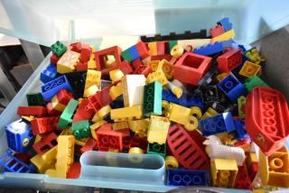 Lot of Lego building blocks in bright colors stored in a hard plastic case. Various shapes and sizes included.