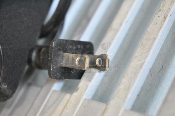 Close-up of a power plug's prongs, likely related to the auction item of three monitors: Asus VG249, Samsung S23C350H, and HP.