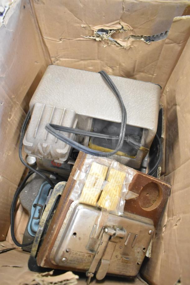 Box containing various items including a Mansfield 950 8mm Editor, cords, and equipment; visible wear on the box.