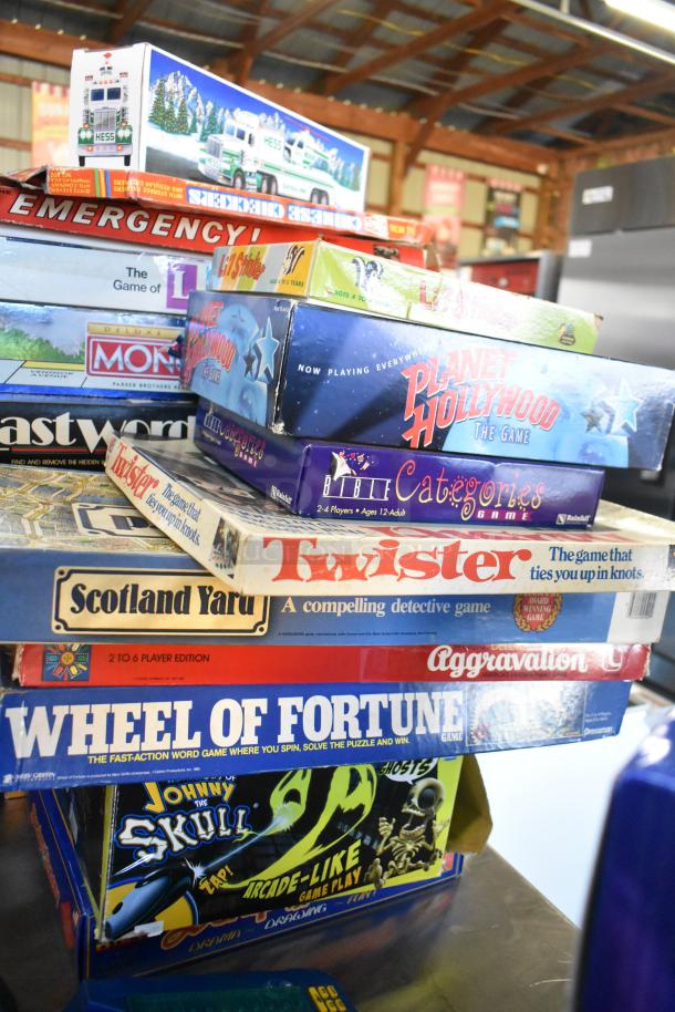 A stacked assortment of board games including Monopoly, Twister, Wheel of Fortune, and Scotland Yard. Various conditions.
