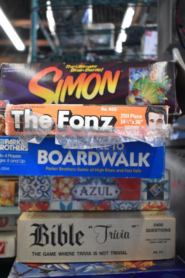 Stack of board games including "Simon," "The Fonz," "Advance to Boardwalk," "Azul," and "Bible Trivia," some with visible wear.