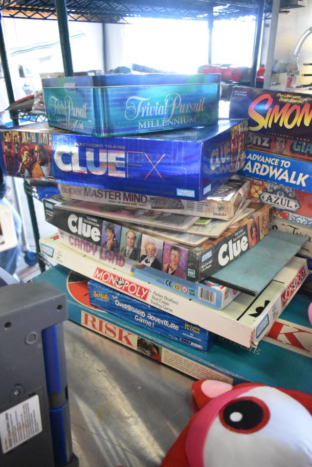 Stack of board games including Trivial Pursuit Millennium, Clue FX, and Monopoly, with visible wear on boxes.