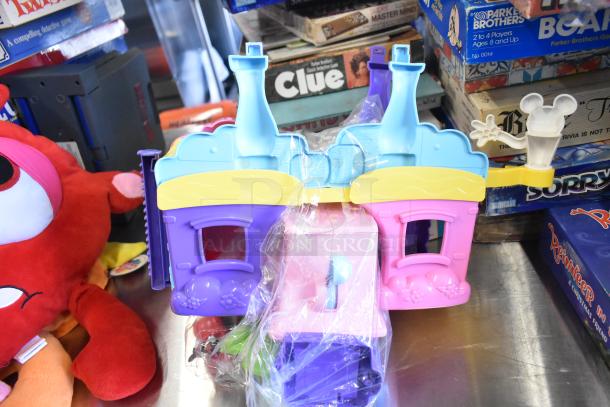 Tier lot includes colorful plastic toy house, plush toy, and assorted board games like Clue and Sorry, in good condition.