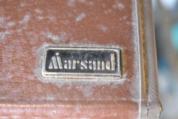 Vintage Marsand bag with metal label, showing signs of wear, part of an auction lot including various items.