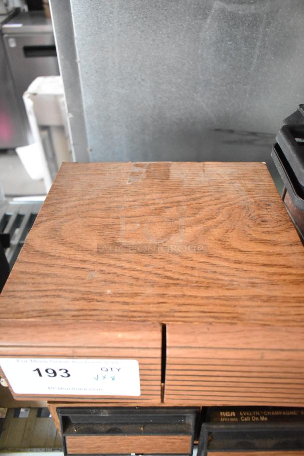 Wooden box with visible grain, containing cassette tapes. Label reads "For More Great Auctions Visit: PCI Auctions, Item 193, QTY x 8."