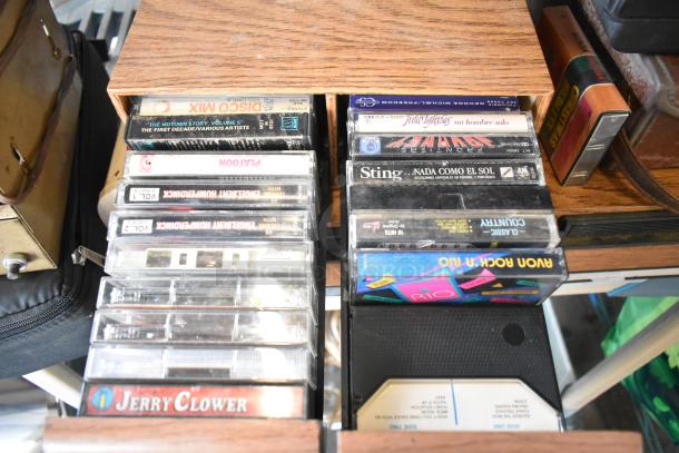 Assorted items including Marsand bag, collection of cassette tapes, and metal mailbox. Various music genres, visible wear.